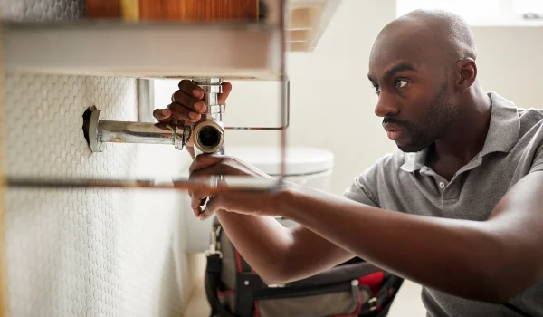 a male plumber fixing a pipe connection from quality plumbing leander in Leander, TX Plumber near me